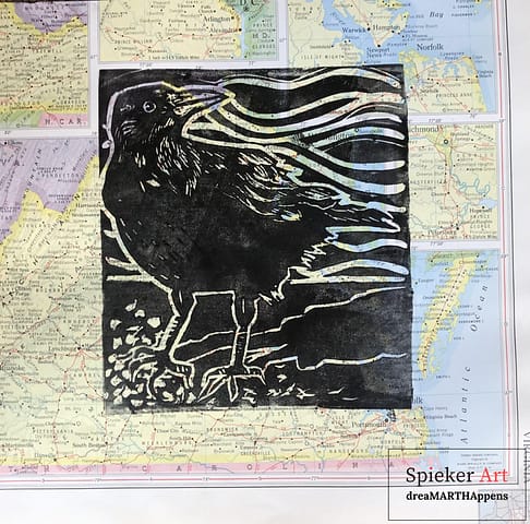 linocut of crow catching the scent on the breeze printed on an antique map